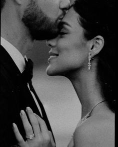 black and white photograph of a bride and groom kissing in front of the camera with their eyes closed