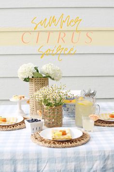 a table topped with plates and vases filled with flowers on top of a blue checkered table cloth