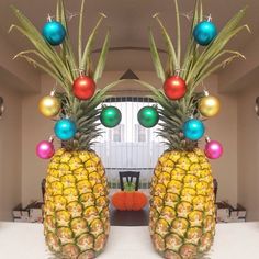 two large pineapples decorated with christmas balls and ornaments in front of a dining room table