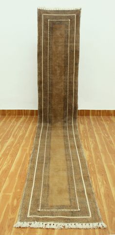 an old rug is on the floor in front of a white wall and wooden floors