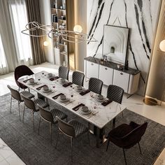 a dining room table set with place settings and chairs, in front of a marble wall