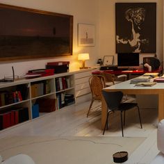 a living room filled with furniture and bookshelves next to a large painting on the wall