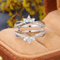 an open ring with three diamonds on it sitting in a velvet box next to some flowers