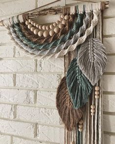 a wall hanging made out of yarn and wood beads with leaves on the top, along with beading