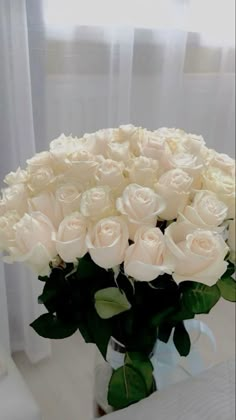 a vase filled with white roses on top of a table