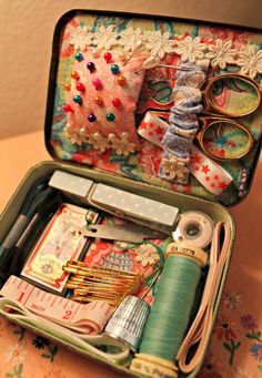 an open suitcase filled with lots of crafting supplies and sewing accessories on top of a table