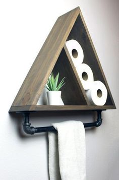 a triangle shaped shelf with toilet paper rolls and a succulent plant on it