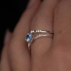 a woman's hand holding a ring with an oval blue topazte on it