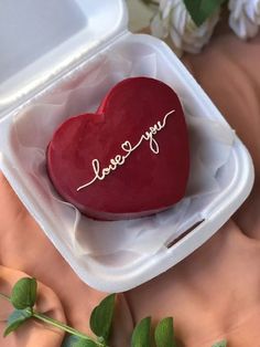 a heart shaped cake with the word love you written on it in a plastic container