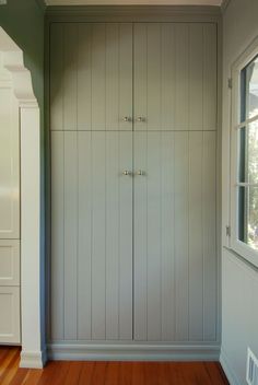 an empty room with wooden floors and white cabinets on the wall, next to a window