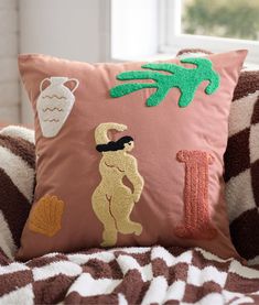 a decorative pillow with an image of a frog and a letter i on it sitting on a bed