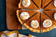 a sliced pumpkin pie on a cutting board with whipped cream around the edges and one slice missing