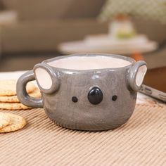 a mug with a koala face is sitting on a table next to crackers