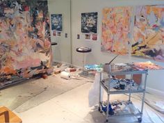 an artist's studio with multiple paintings on the wall