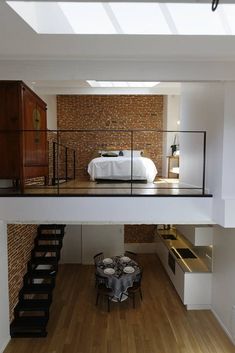 a room with a bed, table and stairs leading up to the second floor bedroom