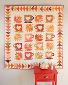 a red table with a quilt on it and a pumpkin sitting on top of it