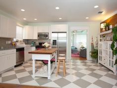 the kitchen is clean and ready to be used for cooking or baking, with white cabinets and checkered flooring