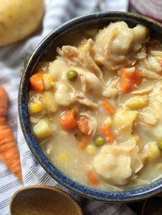 a bowl filled with chicken and dumplings next to carrots