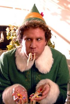 a man wearing a party hat and eating spaghetti with his hands in front of him