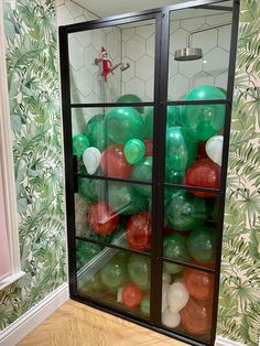 a display case filled with balloons in front of a wallpapered wall and wooden floor