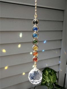 the seven chakras hanging from a gold plated chain on a window sill