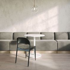 a white table sitting next to a gray couch in front of a wall mounted light fixture