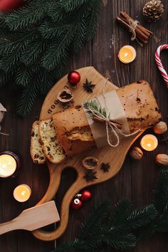 a loaf of bread on a cutting board surrounded by christmas decorations and candles, along with some candy canes