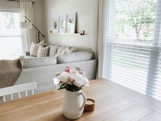 a vase with flowers sitting on top of a wooden table in front of a couch