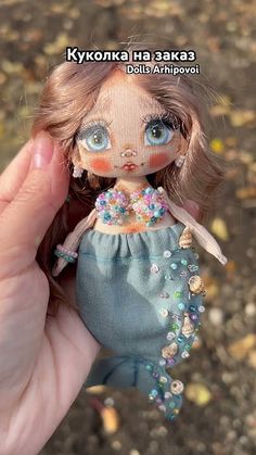 a hand holding a small doll with blue eyes