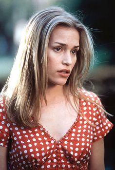 a woman in a red and white polka dot top looking at the camera with her hand on her hip