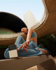 a woman sitting on top of a cement bench next to a laptop computer