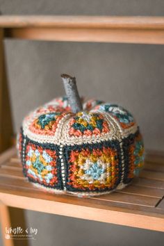 a crocheted pumpkin sitting on top of a wooden shelf