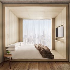 a bed sitting in a bedroom next to a window with a view of the city