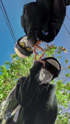 a man in black hoodie holding up a pair of white and yellow shoes with trees in the background