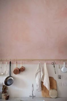 a kitchen with pink walls and hanging utensils