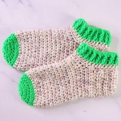 two green and white knitted socks sitting on top of a marble counter