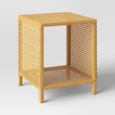 the side table is made out of wicker and has an open shelf for storage