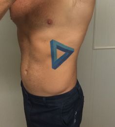 a man with a blue triangle tattoo on his stomach is standing in front of a white wall