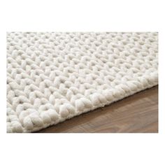 a white rug on top of a wooden floor next to a wood flooring board