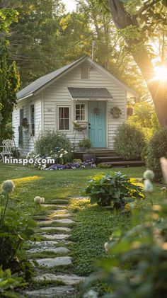 a small white house with a blue door and steps leading up to the front door