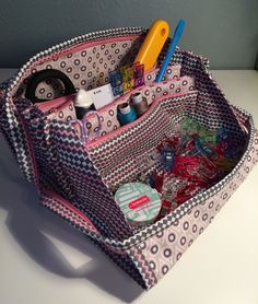 a purse with scissors, buttons and other items in it sitting on a counter top