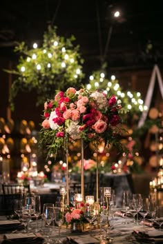 a tall vase filled with pink and red flowers on top of a dining room table