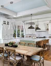 a kitchen filled with lots of white cabinets and wooden tables covered in blue striped chairs