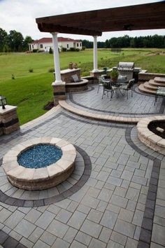 an outdoor patio with seating area and fire pit in the center, surrounded by grass