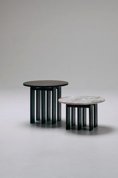 two black and white tables sitting next to each other on a gray surface with grey background