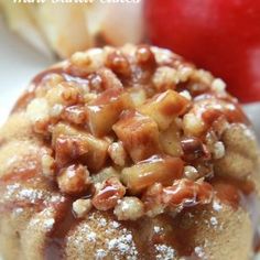 an apple cinnamon roll on a plate with some apples in the backgroung