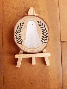 a wooden plaque with a white bird painted on it's face and leaves around the edges