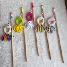 four knitting needles are lined up next to each other on a white surface with crocheted beads