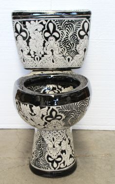 a black and white toilet sitting on top of a cement floor next to a wall