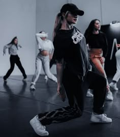 a group of young people standing around each other in front of a white wall with dancers behind them